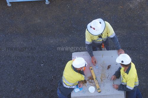 Aerial photo of three mine site workers discussing work. - Mining Photo Stock Library