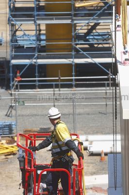 Construction worker in full PPE including chest harness in EWP. - Mining Photo Stock Library