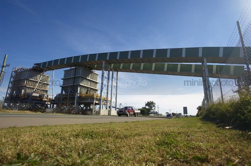 Enclosed coal conveyor crossing high over a road. - Mining Photo Stock Library