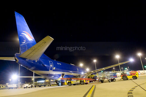 Conveyors loading a large cargo plane at night at airport - Mining Photo Stock Library