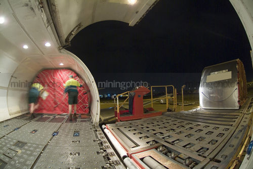 Workers loading the hold of a cargo plane at airport. shot from inside plane - Mining Photo Stock Library