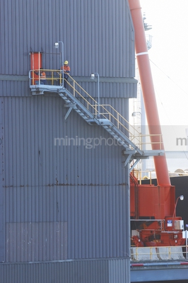 Two workers in full PPE completing maintenance on external stairs at a mine site port. - Mining Photo Stock Library