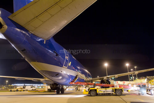 Cargo plane being loaded with freight by conveyor at night - Mining Photo Stock Library
