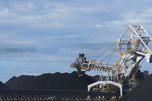 Close up photo of coal reclaimer next to stockpile.  blue sky behind. - Mining Photo Stock Library