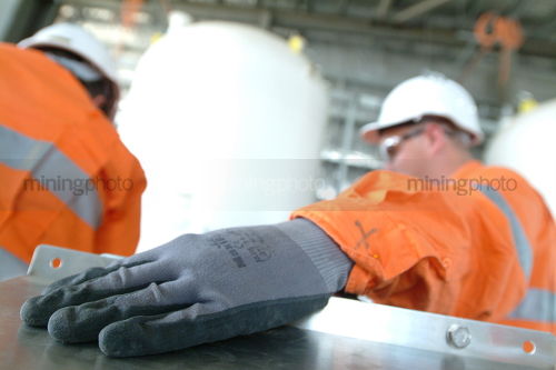 Worker in full PPE inside factory with gloves really close to camera - Mining Photo Stock Library