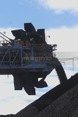 Close up silhouette of a coal loader stockpiling coal. - Mining Photo Stock Library