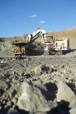 Vertical photo of digger excavator loading a 789 haul truck in open cut mine site.  vertical photo shot from ground level. - Mining Photo Stock Library