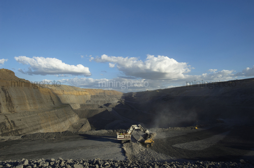Great wide open cut mine site photo of a digger loading a 789 haul truck.  clearly see benching and depth of open cut in background. - Mining Photo Stock Library