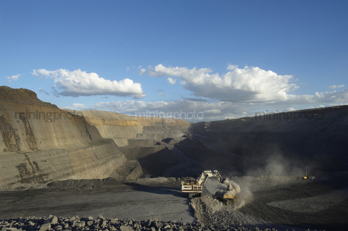 Great wide open cut mine site photo of a digger loading a 789 haul truck.  clearly see benching and depth of open cut in background. - Mining Photo Stock Library