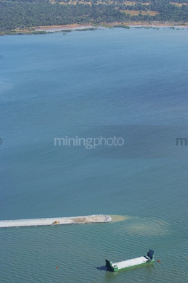Aerial photo of a barge carrying gravel and in the background is a dozer pushing spoil out to make reclaimed land. - Mining Photo Stock Library