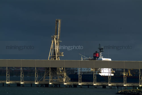 Shiploader and wharf and ship on water after a storm - Mining Photo Stock Library