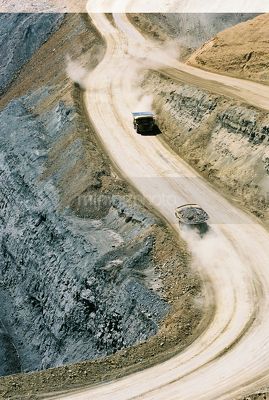 Big trucks on open cut haul road above high wall coal seam aerial vertical image - Mining Photo Stock Library