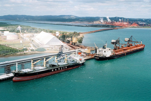 2 ships being unloaded with different product with both processing plants in the background - Mining Photo Stock Library