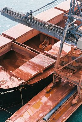 Looking down into ships holds as bauxite is being unloaded by shiploader crane.  aerial closeup image - Mining Photo Stock Library