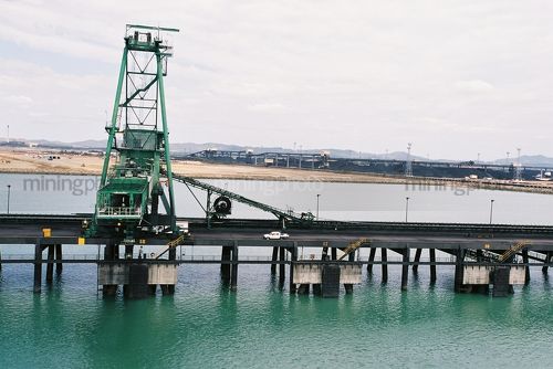 Coal shiploader on wharf with coal stockpile in background - Mining Photo Stock Library