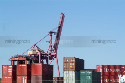Closeup of ship containers stacked on wharf with ship loader in background.  - Mining Photo Stock Library