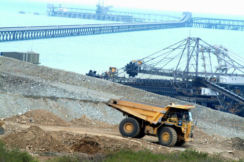 Long wharf to coal terminal with coal reclaimers in middle and large haul truck involved in construction in foreground - Mining Photo Stock Library