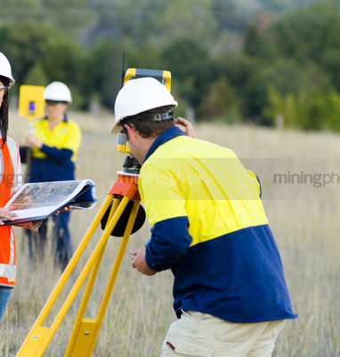 Surveyor and linesperson in fuyll PPE working in the field - Mining Photo Stock Library