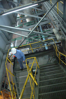 Worker in full PPE walking down stairs inside power station or factory - Mining Photo Stock Library
