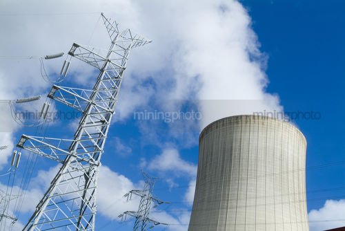 Cooling tower and transformer tower at power station with bright blue sky behind - Mining Photo Stock Library
