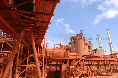 Red conveyors and storage towers inside a refinery - Mining Photo Stock Library