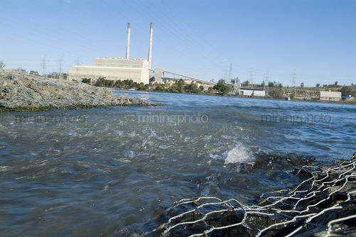 Water inlet into lake with power station in background - Mining Photo Stock Library