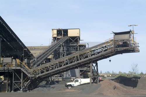 Light vehicle in foreground with conveyors and wash processing plant of mine site behind. - Mining Photo Stock Library