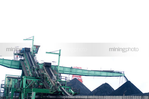 Green ship loader stockpiling coal  at port facility - Mining Photo Stock Library