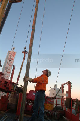 Worker in full PPE centering pipe on a drill rig - Mining Photo Stock Library