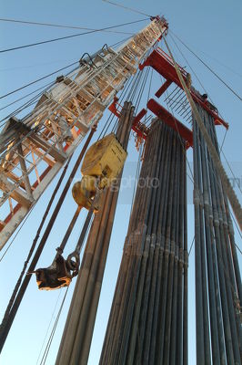 Looking up the derrick on a drill rig with stacked pipe casings hanging - Mining Photo Stock Library