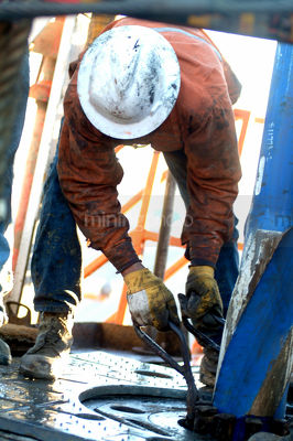 Worker on drill rig floor working at the derrick - Mining Photo Stock Library