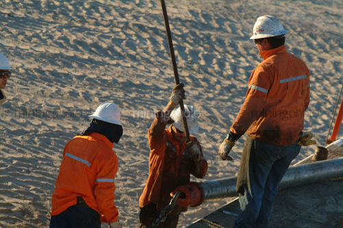 Drill rig workers handling pipe casings - Mining Photo Stock Library