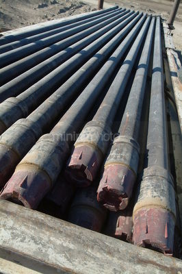 Pipe casings laid out ready to install down drill rig oil gas hole - Mining Photo Stock Library