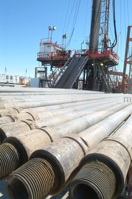 Pipe casing laid out in front of drill rig - Mining Photo Stock Library