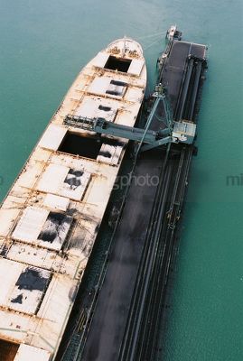 Ship loader loading coal into hold at wharf.  aerial shot - Mining Photo Stock Library