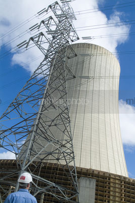 Worker at power station looking up at cooling tower - Mining Photo Stock Library