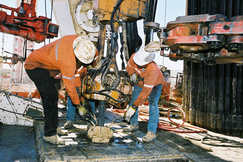 Workers on oil gas rig attaching pipe in the hole - Mining Photo Stock Library