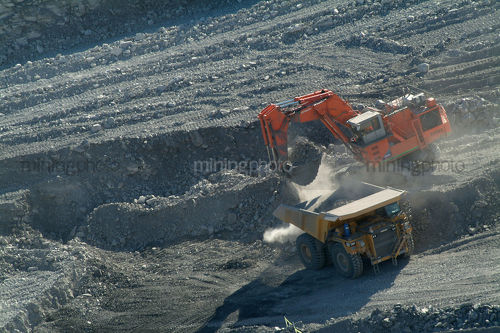 Coal truck being loaded with overburden by digger on opencut mine floor aerial photo - Mining Photo Stock Library