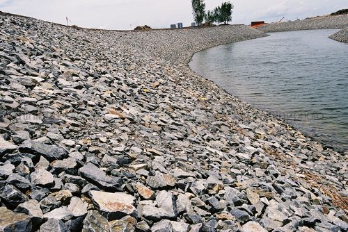 Rock wall edge of dam lake water feature in a property subdivision - Mining Photo Stock Library