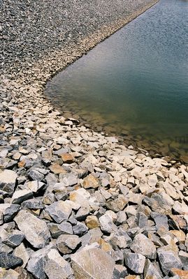 Closeup of the edge of a rock wall leading to dam and water feature - Mining Photo Stock Library