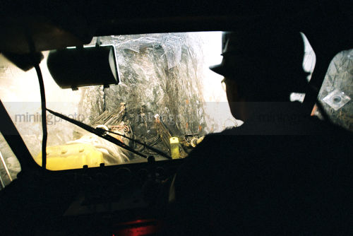 Silhouette of mine worker underground looking out machinery windscreen - Mining Photo Stock Library