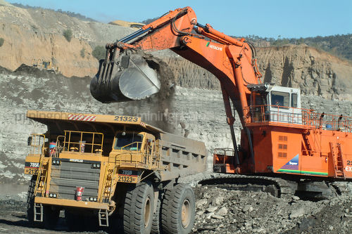 Digger loading a haul truck with overburden on opencut mine floor. high walls behind - Mining Photo Stock Library