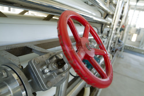 Red wheel type valve on water pipe at purification treatment  plant. - Mining Photo Stock Library