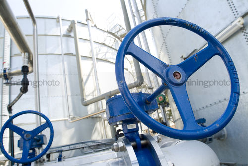 Blue valve tap on water pipes at treatment plant - Mining Photo Stock Library