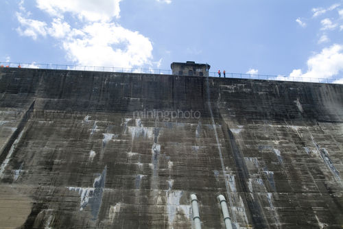 Looking from ground level up at concrete dam wall. - Mining Photo Stock Library