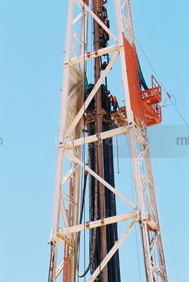 Drill rig worker high up the derrick loading pipe into the hole - Mining Photo Stock Library