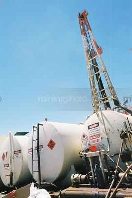 Drill rig derrick with fuel tanks in foreground. - Mining Photo Stock Library