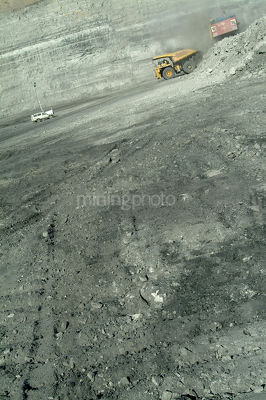 Digger loading haul truck with light vehicle and opencut high walls behind vertical image - Mining Photo Stock Library