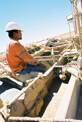 Drill rig worker sitting taking a few minutes to rest in the hot desert sun - Mining Photo Stock Library