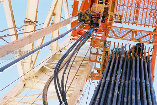 Looking up the derrick on a drill rig site to see stacked pipe ready to load into the drilled hole. - Mining Photo Stock Library